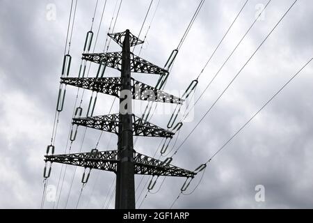 High voltage tower silhouette with electrical wires on storm sky background with dark clouds. Electricity transmission lines, power supply concept Stock Photo