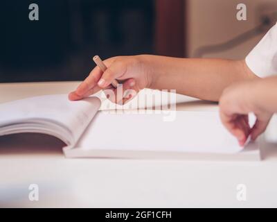 Child learning to draw. Close-up of a child's hands with a white paper book. Back to school Stock Photo
