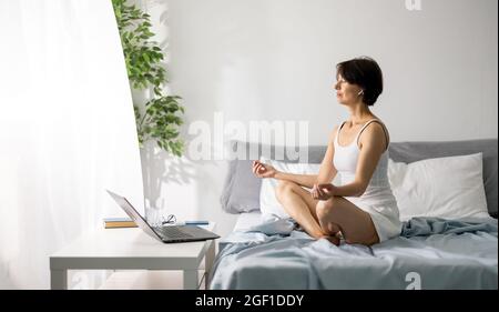 Woman meditating on bed Stock Photo