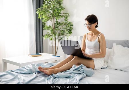 Freelancer with laptop in bed Stock Photo