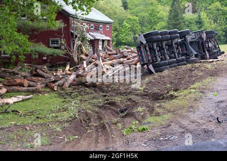 A log hauling truck accident in Hoffmeister, NY USA involving a logging truck rolling on its side and dumping a load of logs on the front of a house. Stock Photo