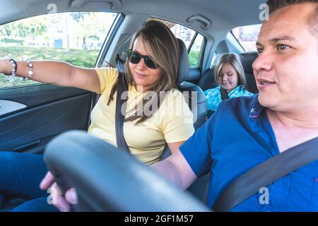 A man drives the car while his wife shows him the way and his daughter in the back seat Stock Photo