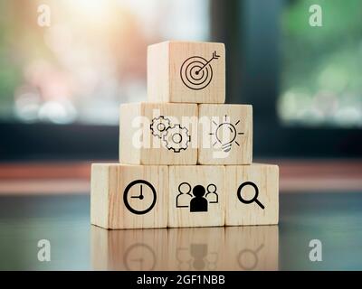 Modern business icons on wooden cube blocks, pyramid steps on desk. Leadership, key success, business strategy and Action plan concept. Stock Photo