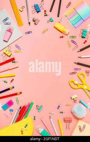 Creative student desk with school supplies and copy space in center. Top view or flat lay. Trendy back to school flat lay on pink background. Vertical Stock Photo