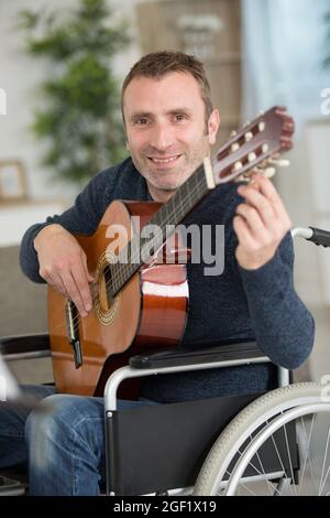 disabled man at home playing the guitar Stock Photo