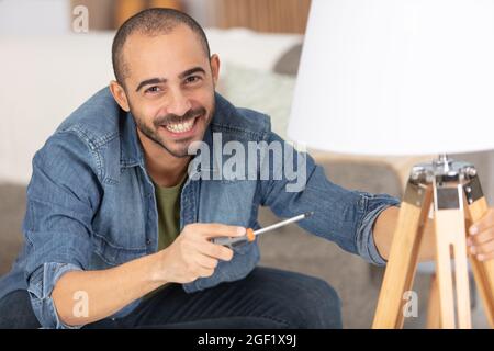 a mans hand twists a light bulb from a lampshade Stock Photo