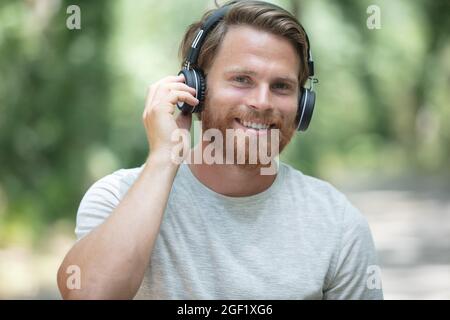 portrait of young bearded man outdoors wearing headphones Stock Photo