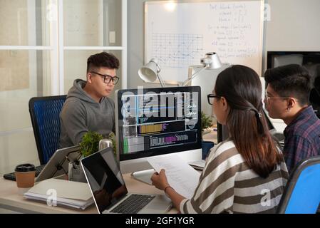 Young woman checking programming code on computer screen and comparing with code on printed document Stock Photo