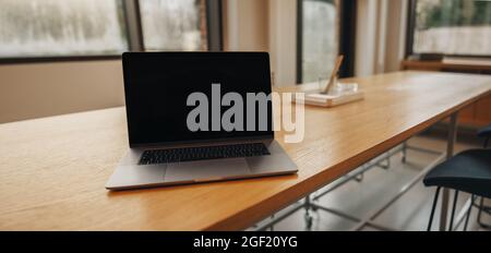 Laptop with black screen in empty coworking office space. Blank computer screen for content placement. Stock Photo