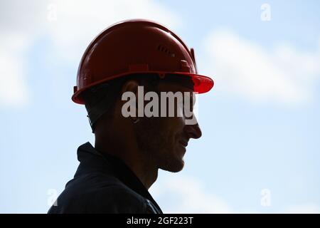 Backlit side view of construction worker wearing hardhat while standing against sky in background, copy space Stock Photo
