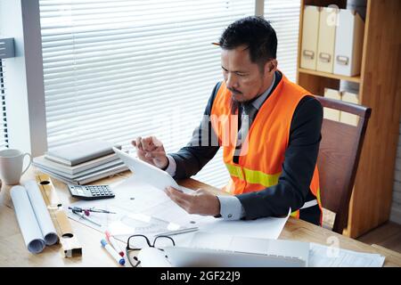 Civil engineer filling document with information on construction project on tablet computer Stock Photo