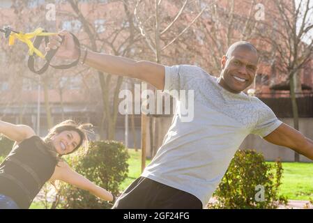Male and female athletes doing lateral arm exercises with fitness straps. Stock Photo