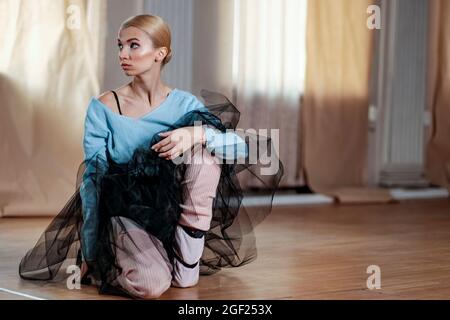 Female ballet dancer performs stretching exercises before beginning a dance rehearsal. Stock Photo