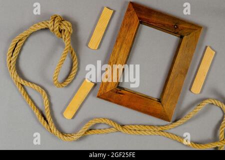 Empty photo frame and rope against a gray background. Wooden picture frame. Natural rope. Wooden planks. Top view. Stock Photo