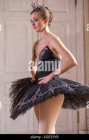 Young ballerina dressed in a black tutu with a crown looks sad as she prepares for a role in a classical ballet in Saint Petersburg, Russia Stock Photo