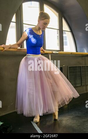 Young ballet dancer dressed in a tutu practices her dance in a rehearsal hall in Saint Petersburg in preparation for a performance. Stock Photo