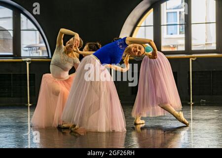 Four young female ballet dancers dressed in colorful tutus rehearse for a performance in a rehearsal hall Stock Photo