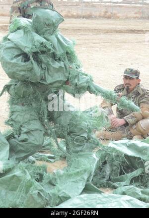 PAKTYA PROVINCE, Afghanistan – An Afghan Nation Army basic trainee covers himself with sandbag material to show an example of camouflage effectiveness during a course at the Regional Military Training Center of Gardez, Feb. 25, 2013.  The course is a nine-week course, and will graduate nearly 600 ANA soldiers at the end of March 2013. (U.S. Army photo by Spc. Tianna Waite, 115th Mobile Public Affairs Detachment) Stock Photo