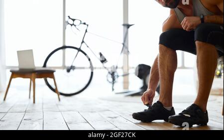 Young man putting on sports shoes at home Stock Photo