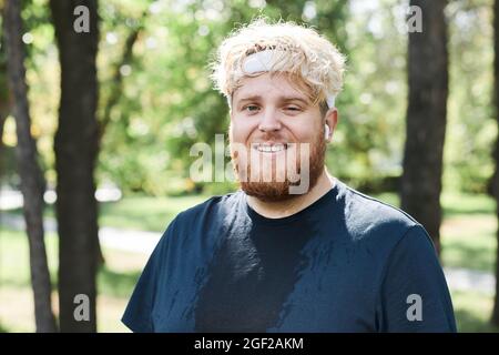 Portrait of overweight bearded man smiling at camera while training in the park Stock Photo