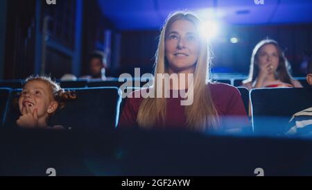 Front view of cheerful young woman in the cinema, watching film. Stock Photo