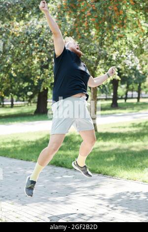 Overweight man happy to win he running to finish line first during training in the park Stock Photo