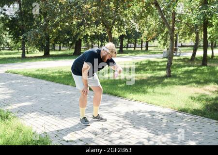 Runner checking results on his fitness tracker during sports training in the park Stock Photo