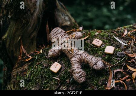 A woven voodoo doll of threads, moth and runes in ritual in mysterious forest. Stock Photo