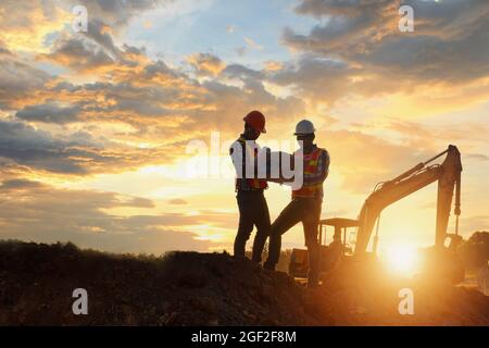 Construction engineers supervising progress of construction project ,Engineering Consulting People on construction site holding blueprint in his hand. Stock Photo