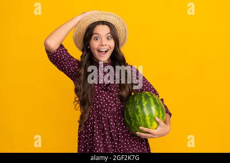 amazed kid holding fresh ripe water melon fruit in summer straw hat, nutrition Stock Photo