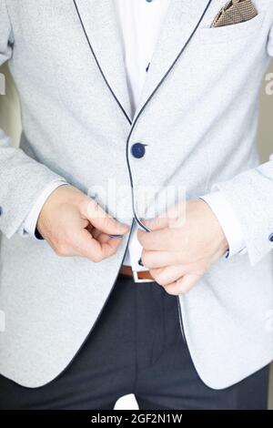 groom wears a vest and closes with two hands button links in morning wedding preparation. High quality photo Stock Photo