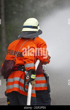 two firefighters with a fire hose , Germany Stock Photo