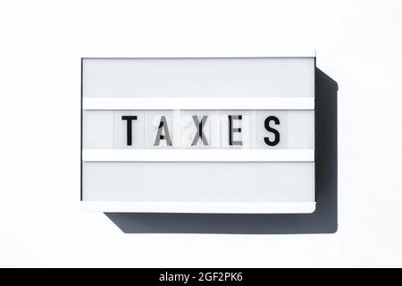 Lightbox board on a white background with the words TAXES in black letters. Currency, cash Stock Photo
