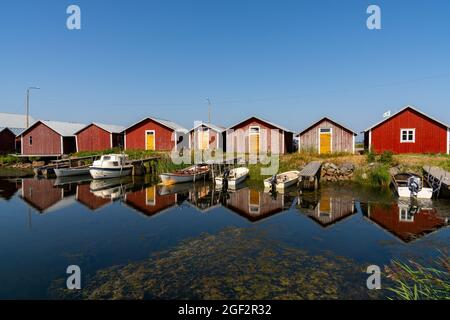 Svedjehamm, Finland - 28 July, 2021: colorful fishing cottages and boats reflected in the water under a blue sky Stock Photo