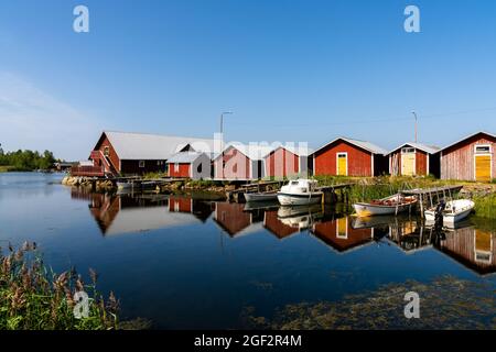 Svedjehamm, Finland - 28 July, 2021: colorful fishing cottages and boats reflected in the water under a blue sky Stock Photo