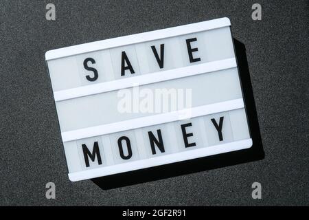 Lightbox board on a black background with the words SAVE MONEY in black letters. Money Stock Photo