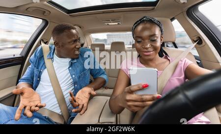 Black man yelling at his wife checking phone while driving Stock Photo