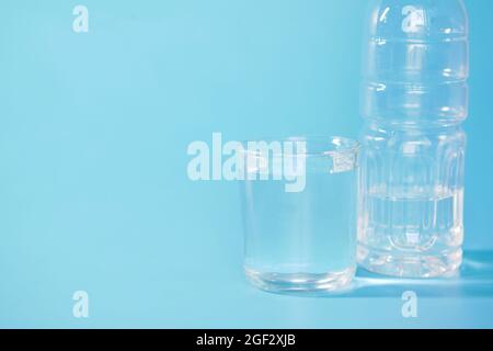 fresh drinking water in a plastic bottle and glass of water on blue  Stock Photo