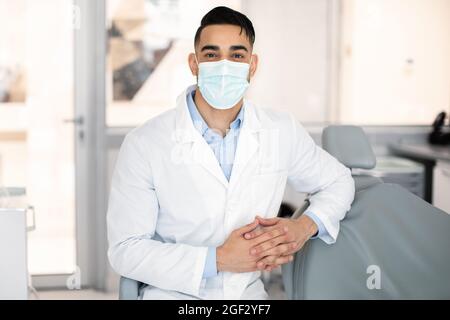Portrait Of Young Middle-Eastern Dentist Wearing Protective Medical Mask Posing At Workplace Stock Photo