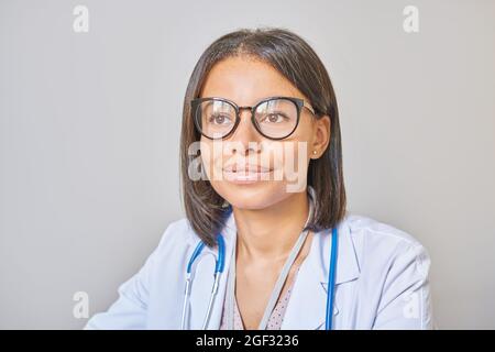Smiling afro american woman professional doctor in spectacles with stethoscope on shoulders at work Stock Photo