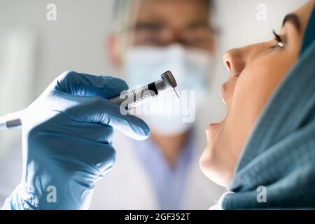 Closeup Of Arab Dentist Using Dental Drill For Muslim Female Patient Treatment Stock Photo