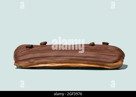 Chocolate eclair with coffee beans on light blue background isolated Stock Photo