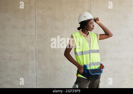 Waist up portrait of young African-American woman working at construction site and looking away, copy space Stock Photo