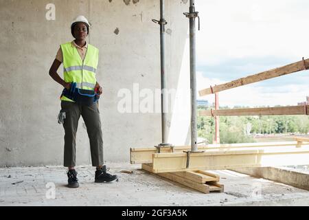 Full length portrait of young African-American woman working at construction site and smiling at camera, copy space Stock Photo