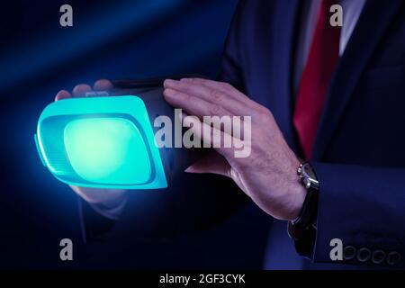 Virtual glasses in the hands of a business man on a dark background close up. Stock Photo