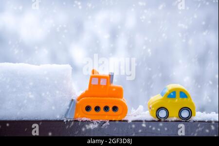 Toy snow plow in winter landscape. Road safety concept, street cleaning work, transportation in bad weather. Stock Photo