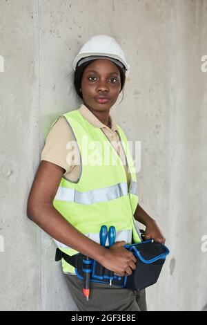 Vertical waist up portrait of young African-American woman working at construction site in engineering Stock Photo