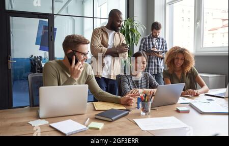 Working on project together. Group of multiracial coworkers communicating, talking, sharing fresh ideas while working in the modern coworking space Stock Photo