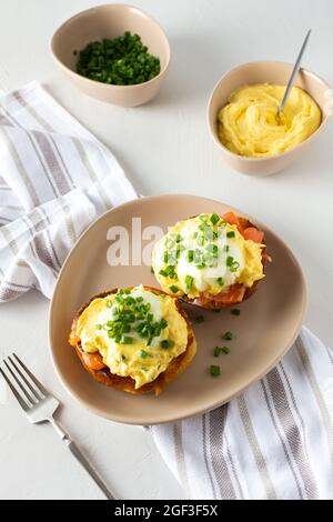 Delicious hearty breakfast, eggs Atlantic in a plate on a white background, round fried bun with salmon and eggs Benedict, hollandaise sauce Stock Photo