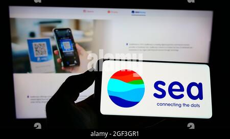 Person holding smartphone with logo of Singaporean technology conglomerate Sea Limited on screen in front of website. Focus on phone display. Stock Photo